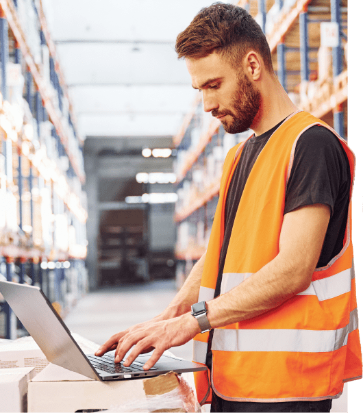 Focussed warehouse worker using a laptop